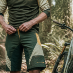 vététiste ajuste short vtt sur sentier forestier